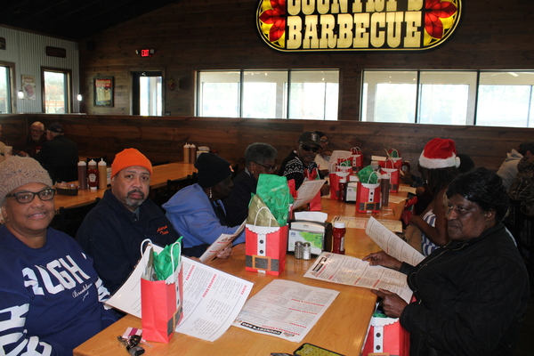 Seniors sitting around the table at the BBQ restaurant.  Santa gift bags are in front of each senior on the table