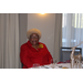  Older lady dressed in a red suit sitting at her dinner table at the Christmas luncheon 