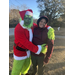  The Grinch in a santa suit and his green outfit hugging a youth resident 