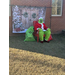  The Grinch sitting outside with a Christmas themed back drop 